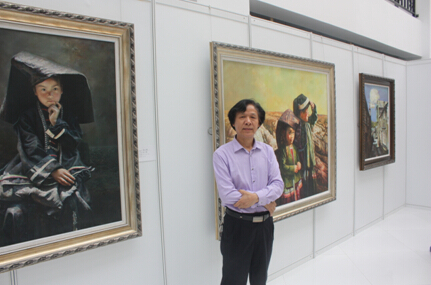 画家覃日群与自己的参展作品