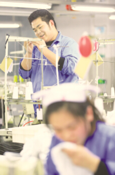 ●男缝纫工杜军强（后）在山东大型纺织企业即墨市即发集团生产服装产品。