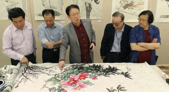 筹委会主席刘建吉先生（中）正在书画艺术展示现场与到会嘉宾进行友好交流。