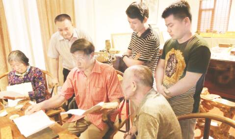 ●胡德生（中）正在细致地点评楠苑公司的家具生产设计图。