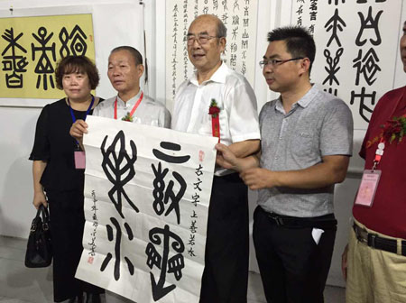 许金美（左2）赠送给中国文联书画艺术中心顾问、中国书协顾问权希军（右2）一幅古文字“上善若水”合影留念。