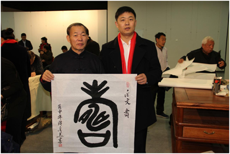 2017年1月2日，国际著名书画艺术大师许金美(左)赠送给中国企业报道总编、中国企业文化促进会企业艺术家工作委员会秘书长薛雷(右)一幅金文“寿”书法作品。