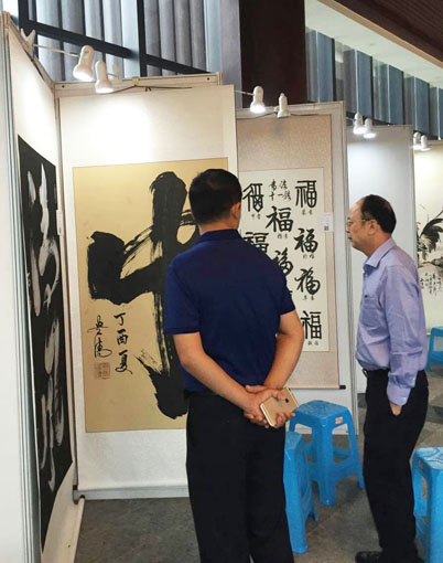 福建泉州市古建公司董事长蒋钦泉和中企报盟信息科学研究院秘书长薛雷在谭贵清老师作品前讨论